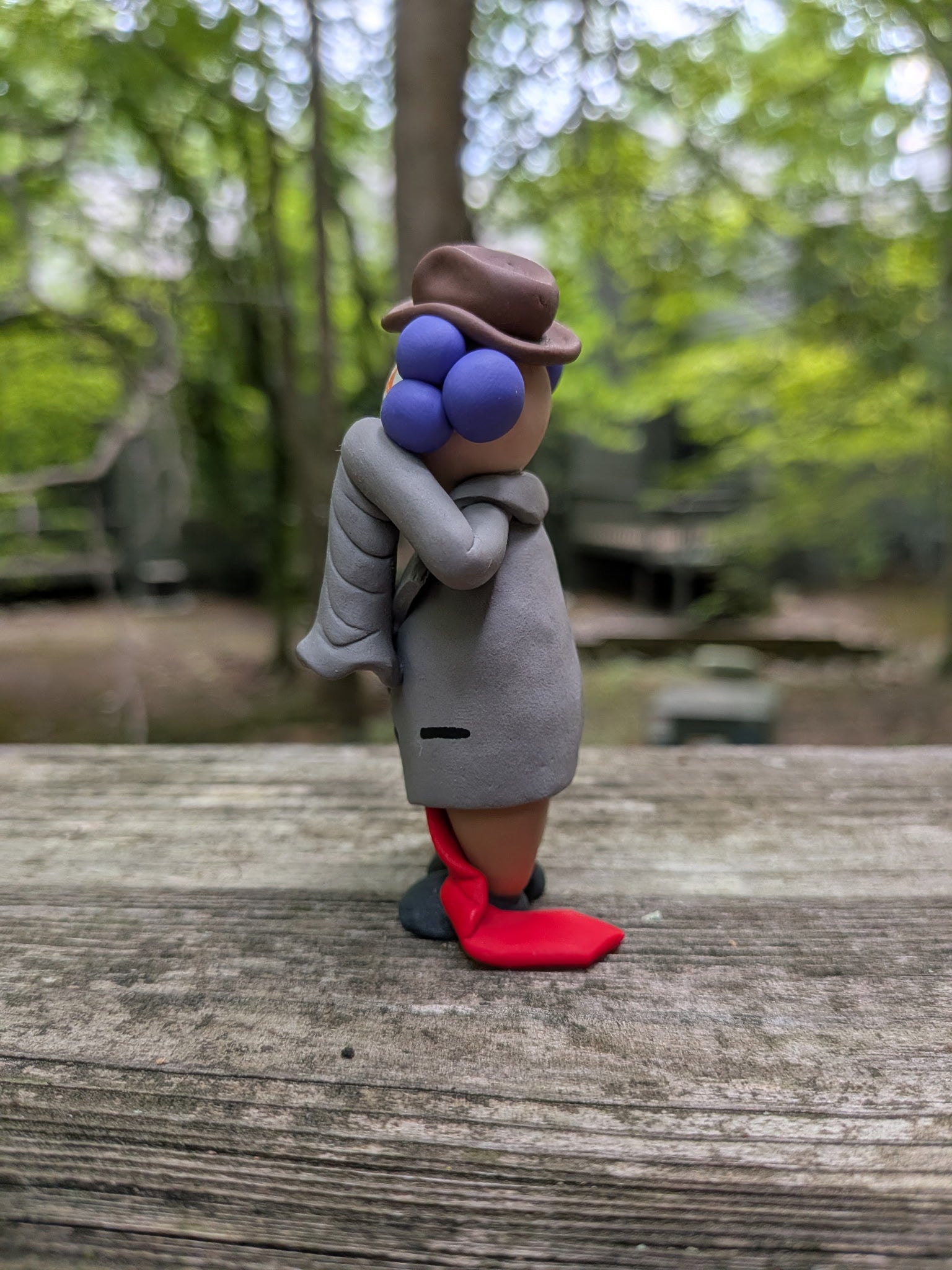 A funny business clown from the left side. He has a long suit jacket with an oversized drooping sleeve that dangles as he wipes a tear away from his left eye. His long red tie is shown dragging on the ground.